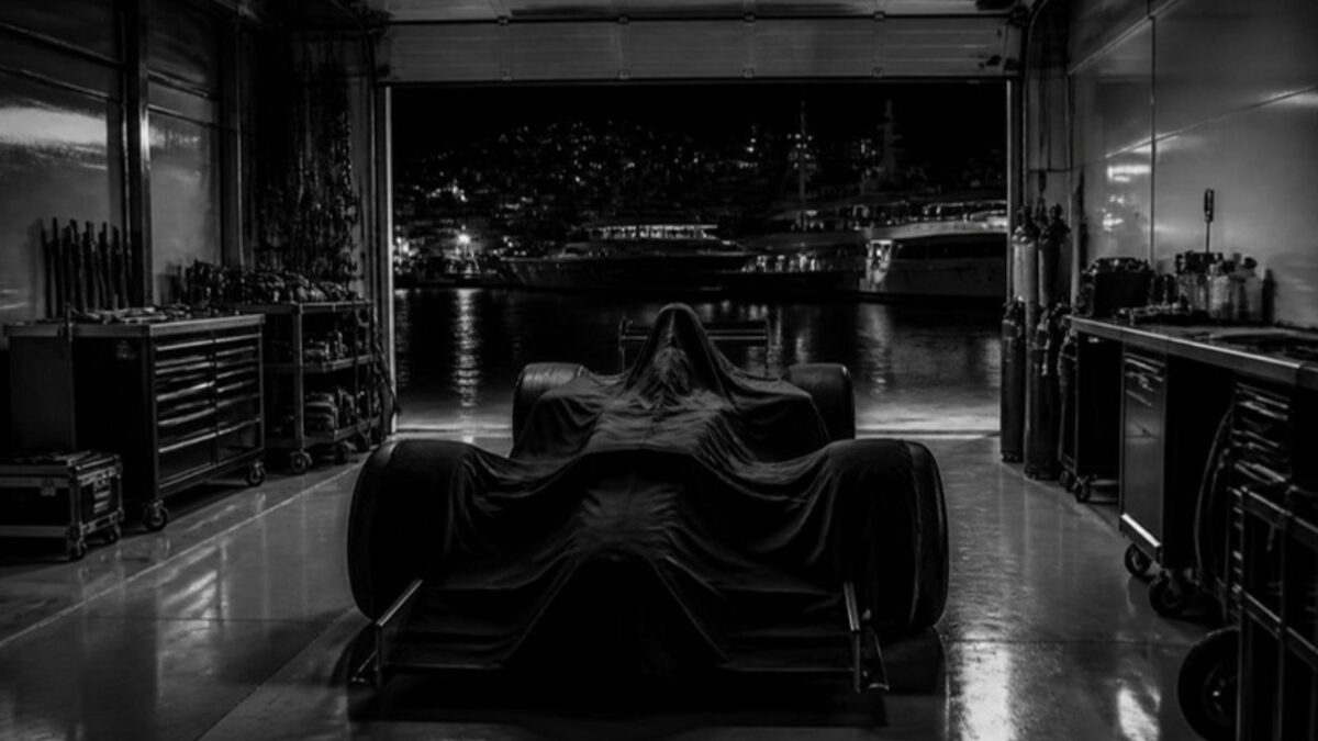 Άδειο γκαράζ Formula 1 τη νύχτα με σκεπασμένο μονοθέσιο και λιμάνι στο βάθος
