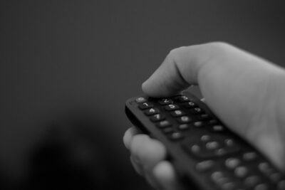 Χέρι που κρατά τηλεχειριστήριο μπροστά από τηλεόραση